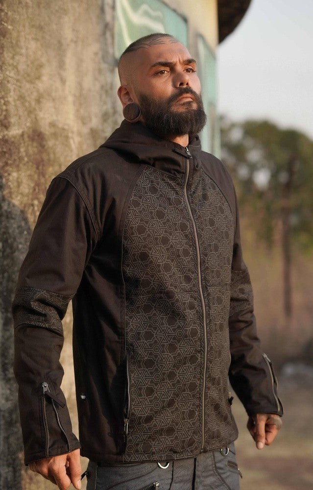 Man wearing a black cotton jacket with a pythagoras v2 patterned design, standing outdoors.