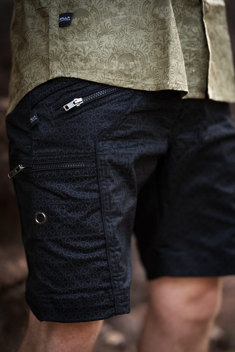 Close-up view of black cotton cargo shorts featuring zipper details and reinforced rivets