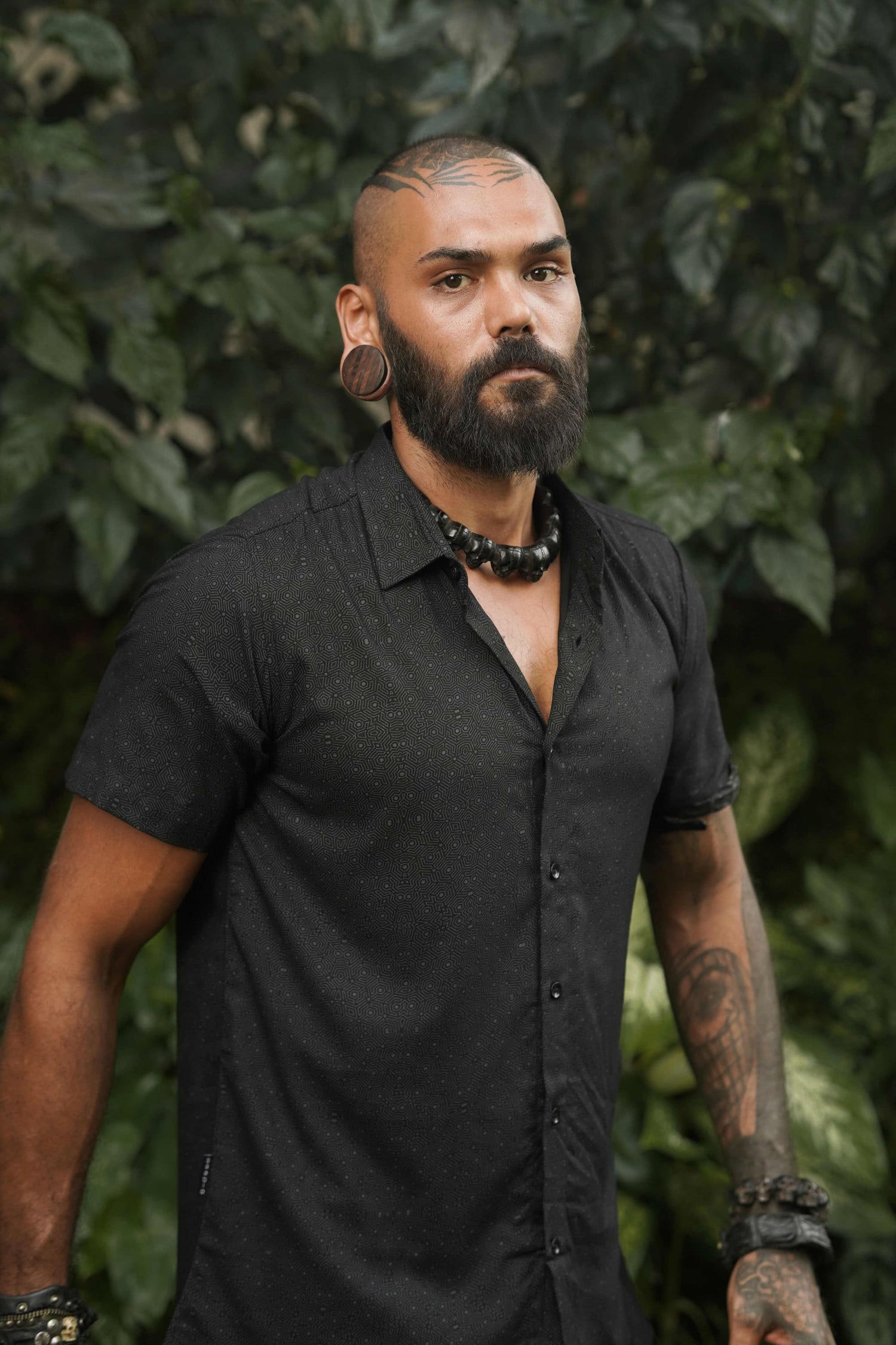 Model wearing a black short sleeve viscose shirt with intricate geometric print – perfect for modern streetwear or festival style.