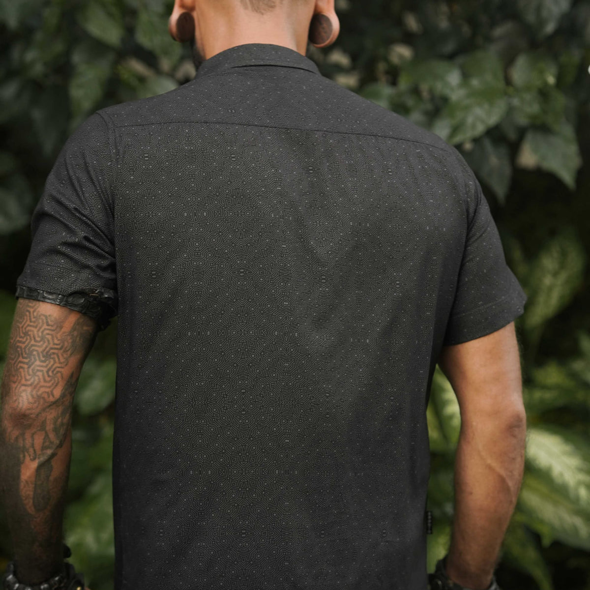 Back view of a men's short sleeve viscose shirt in black with abstract screen-printed pattern, ideal for casual summer wear.