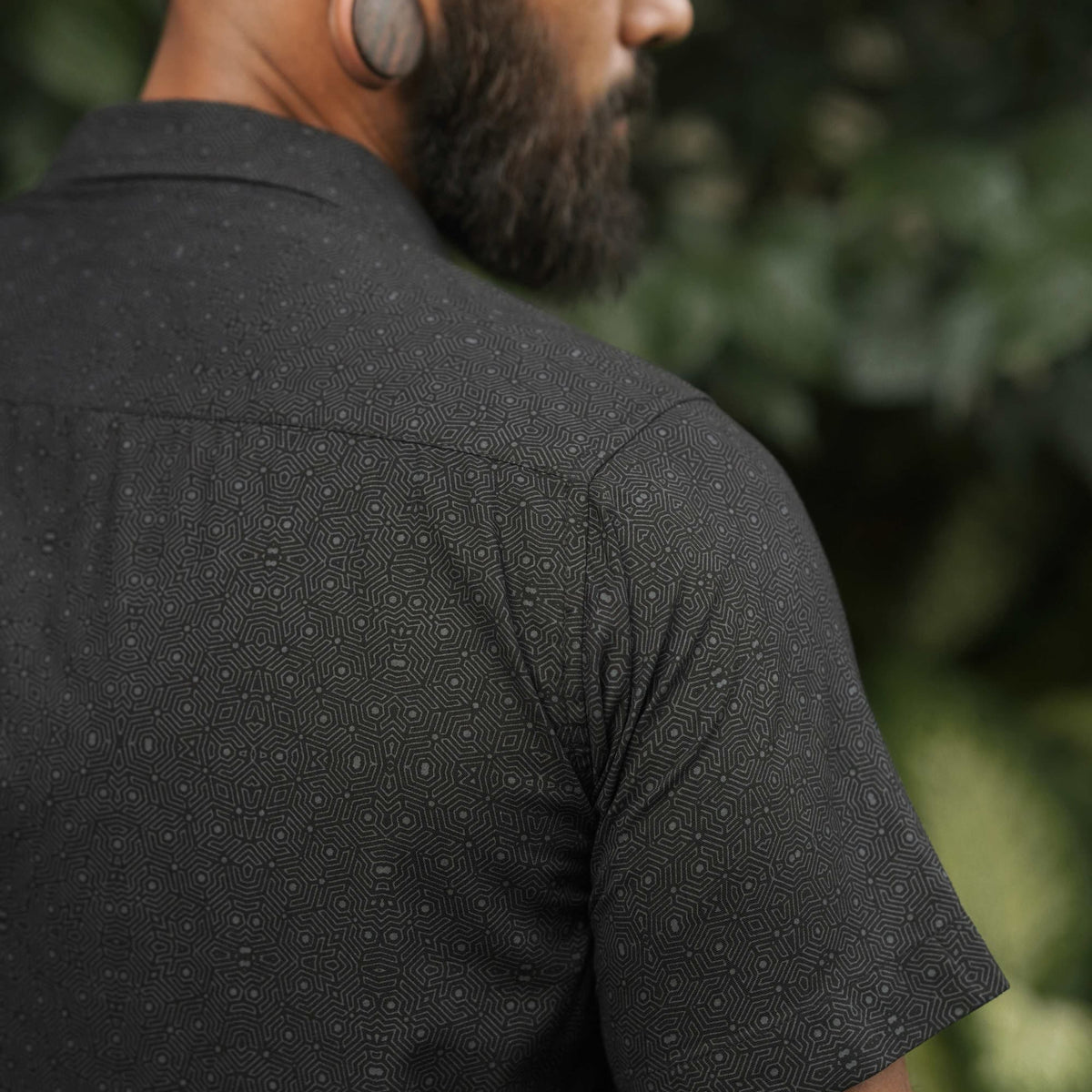 Back angled view of Tetrahedron black men's viscose shirt featuring geometric all-over pattern