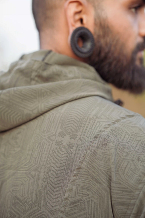 Khaki geometric windbreaker jacket close-up showing detailed Metanoia pattern on shoulder