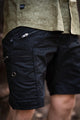 Close-up view of black cotton cargo shorts featuring zipper details and reinforced rivets