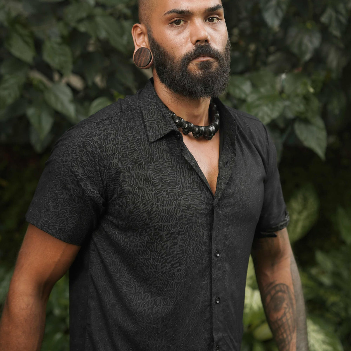 Model wearing a black short sleeve viscose shirt with intricate geometric print – perfect for modern streetwear or festival style.