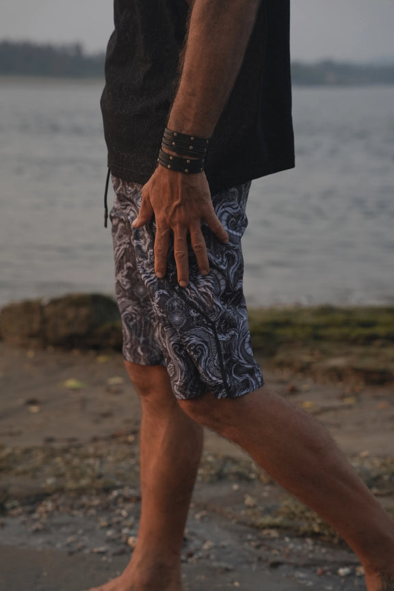 Abstract Dragon psychedelic board shorts for men with monochrome dragon print, shown from the side at the beach.
