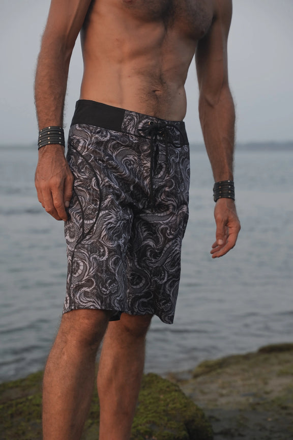 Front view of men's Abstract Dragon board shorts with an intricate monochrome dragon print and contrasting black drawstring waistband.
