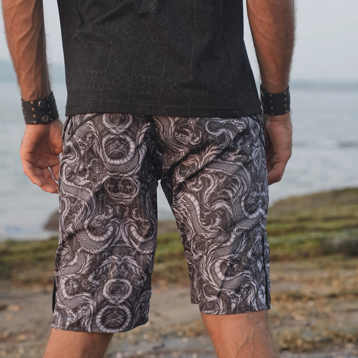 Back view of Abstract Dragon men's swim shorts showing the continuous dragon print and contrasting black waistband.
