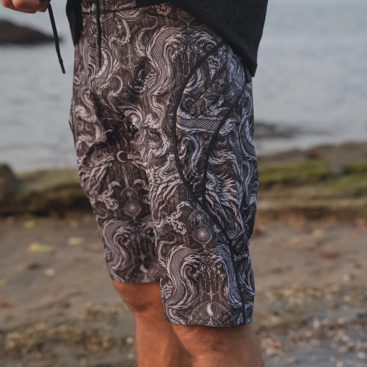 Abstract Dragon psychedelic board shorts with adjustable black drawstring and curved side pocket trim, shown in close-up.