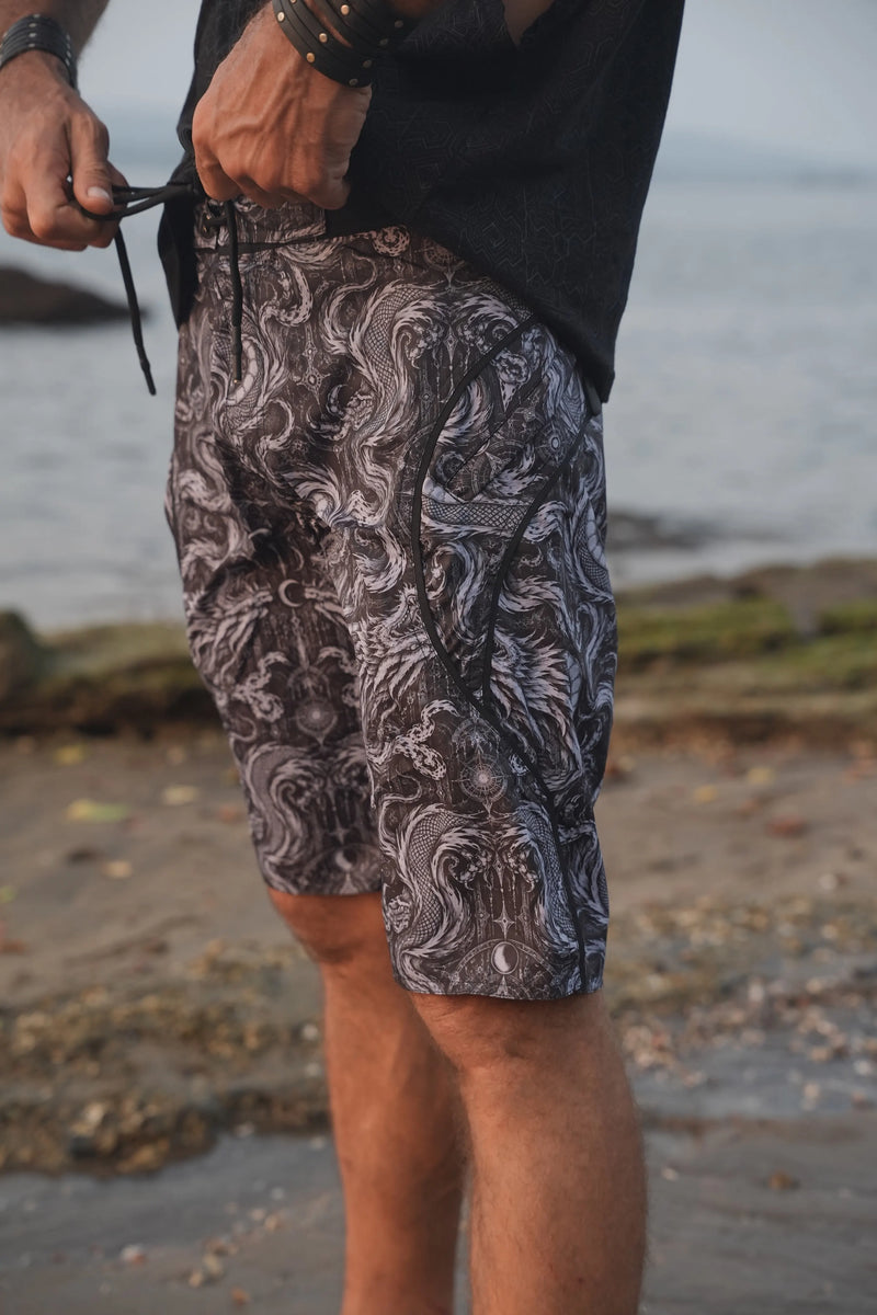 Abstract Dragon psychedelic board shorts with adjustable black drawstring and curved side pocket trim, shown in close-up.