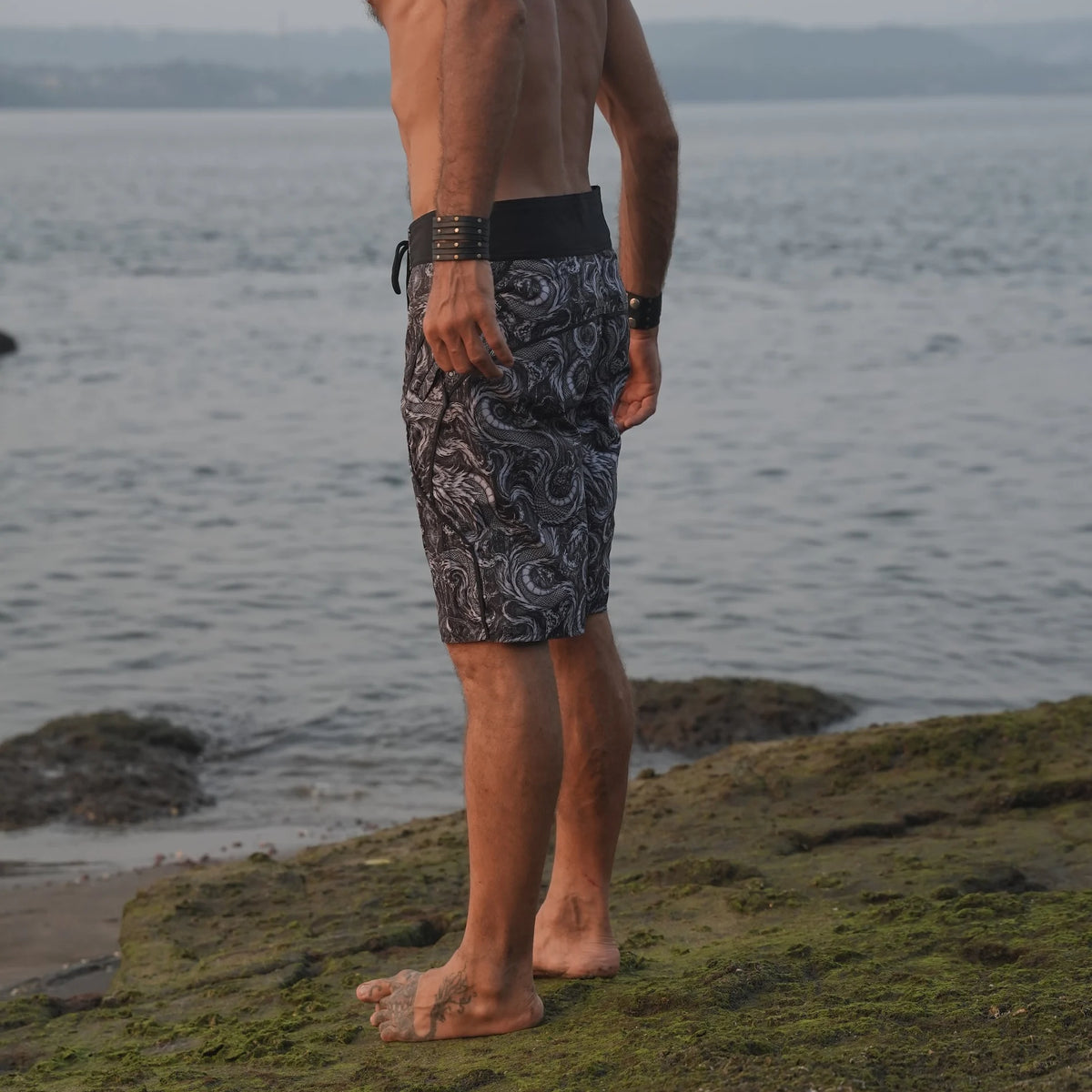 Men's Abstract Dragon psychedelic board shorts featuring detailed black and grey dragon artwork, styled for a relaxed beach look.