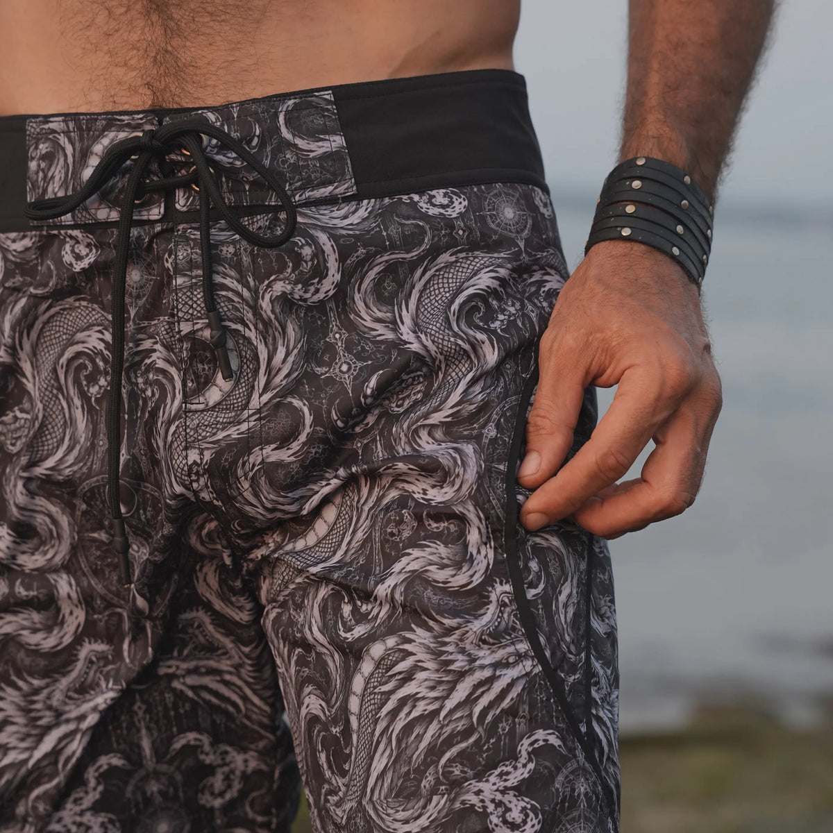 Close-up of Abstract Dragon board shorts showing intricate black and grey dragon artwork, black waistband and adjustable drawstring.
