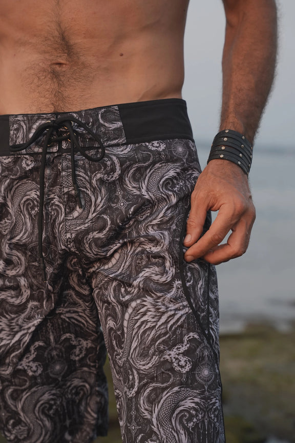 Close-up of Abstract Dragon board shorts showing intricate black and grey dragon artwork, black waistband and adjustable drawstring.
