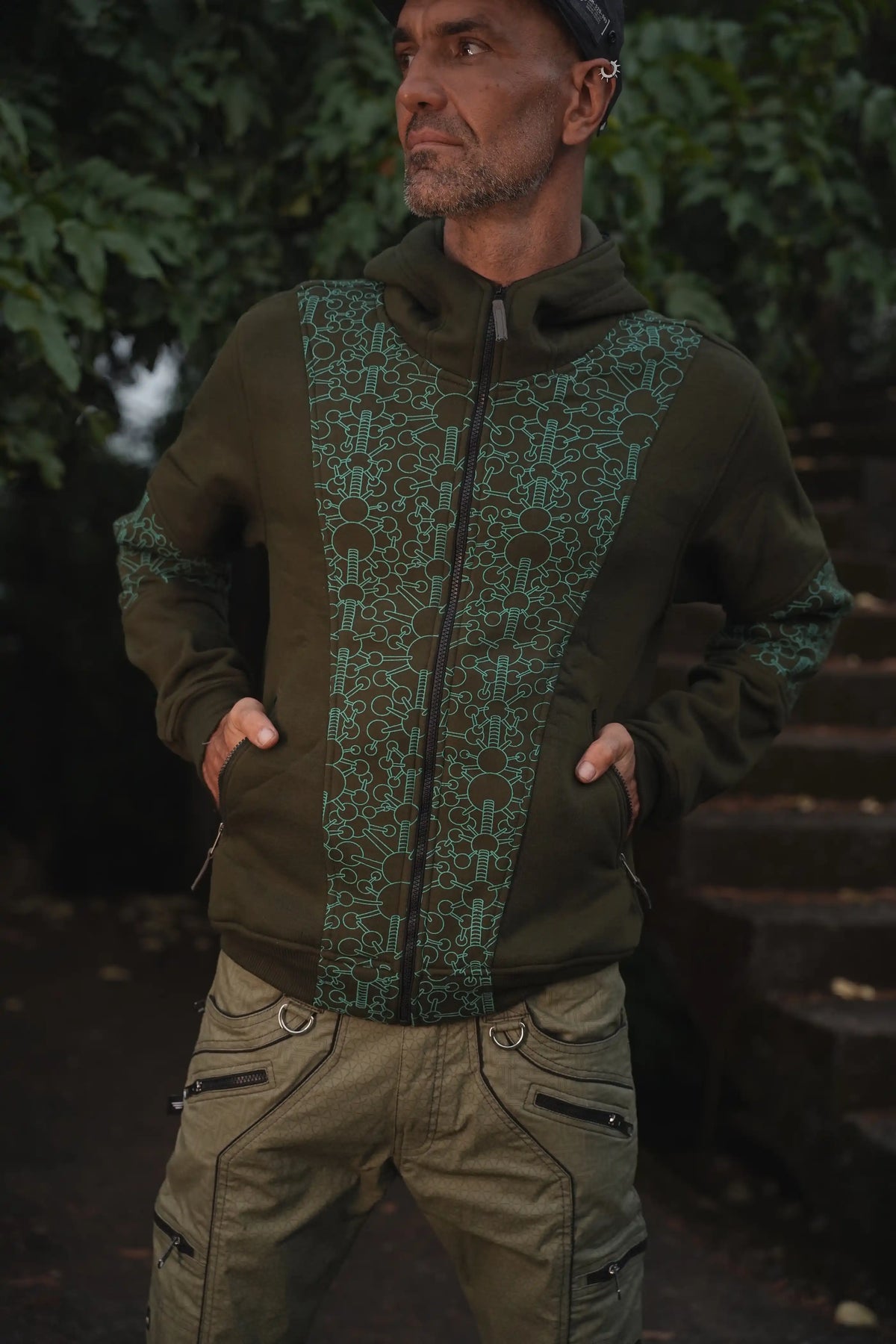Man wearing the Fractal Gravity green psychedelic hoodie with geometric print and full-length front zipper