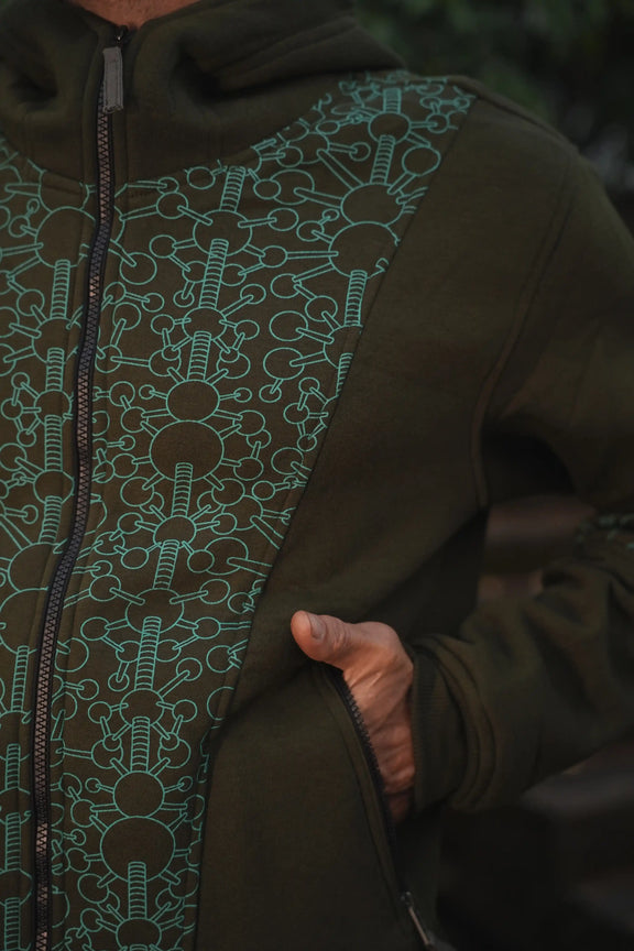 Close-up of the Fractal Gravity hoodie showing its green geometric print and zippered front pocket