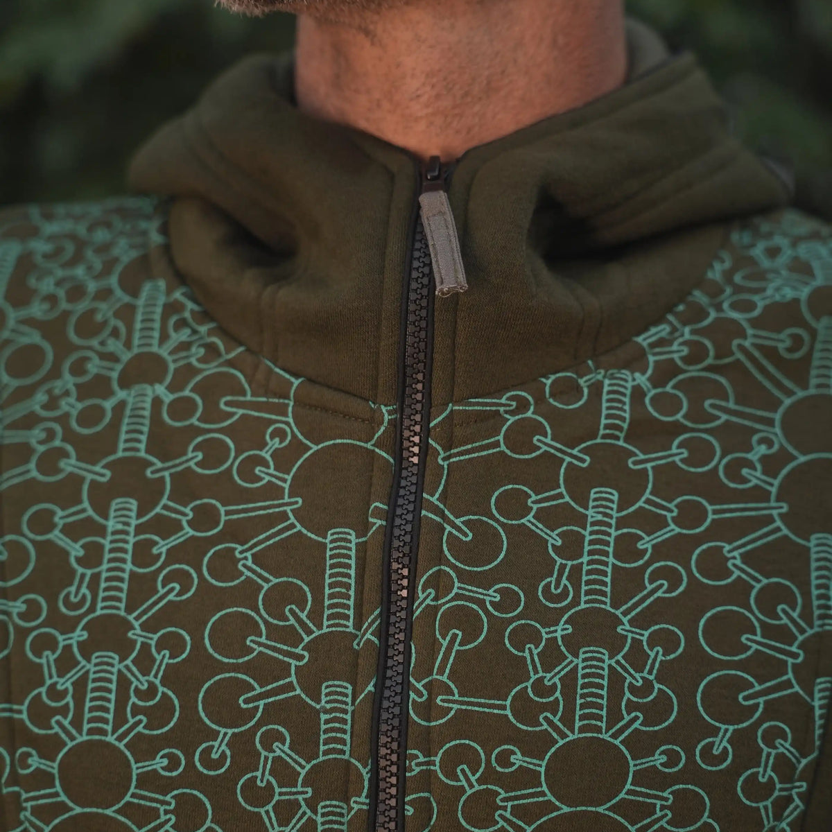 Close-up of the repeating geometric pattern on the Fractal Gravity hoodie in dark olive green