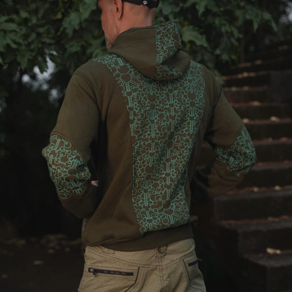 Angled rear view of the Fractal Gravity green psychedelic zip-up hoodie with patterned back and sleeves