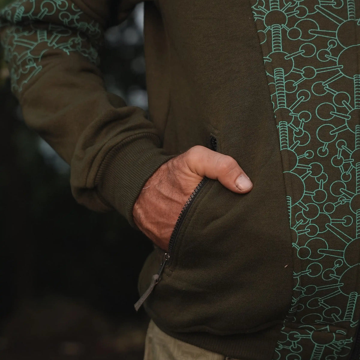 Close-up of a zippered pocket and geometric printed panel on the Fractal Gravity hoodie