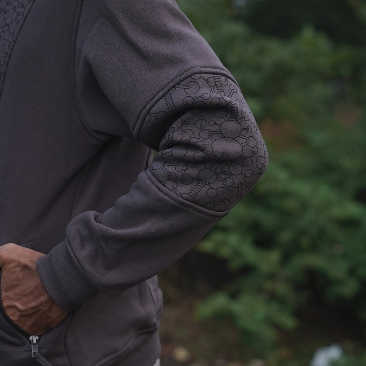 Close-up of the grey hoodie sleeve showing its dark geometric patterned elbow panel