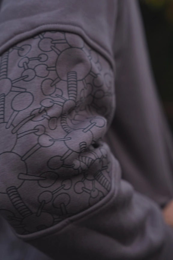 Close-up of the Fractal Gravity grey hoodie elbow panel with repeating geometric artwork