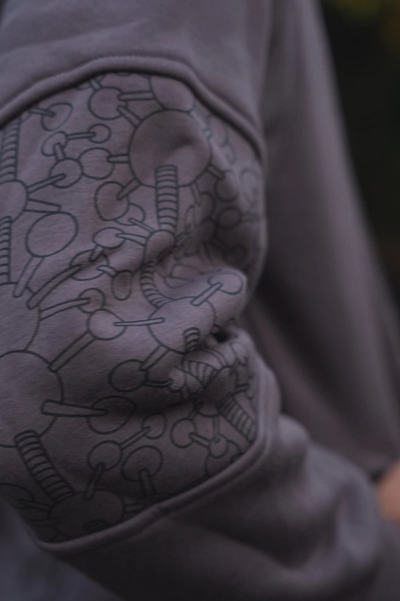 Close-up of the Fractal Gravity grey hoodie elbow panel with repeating geometric artwork