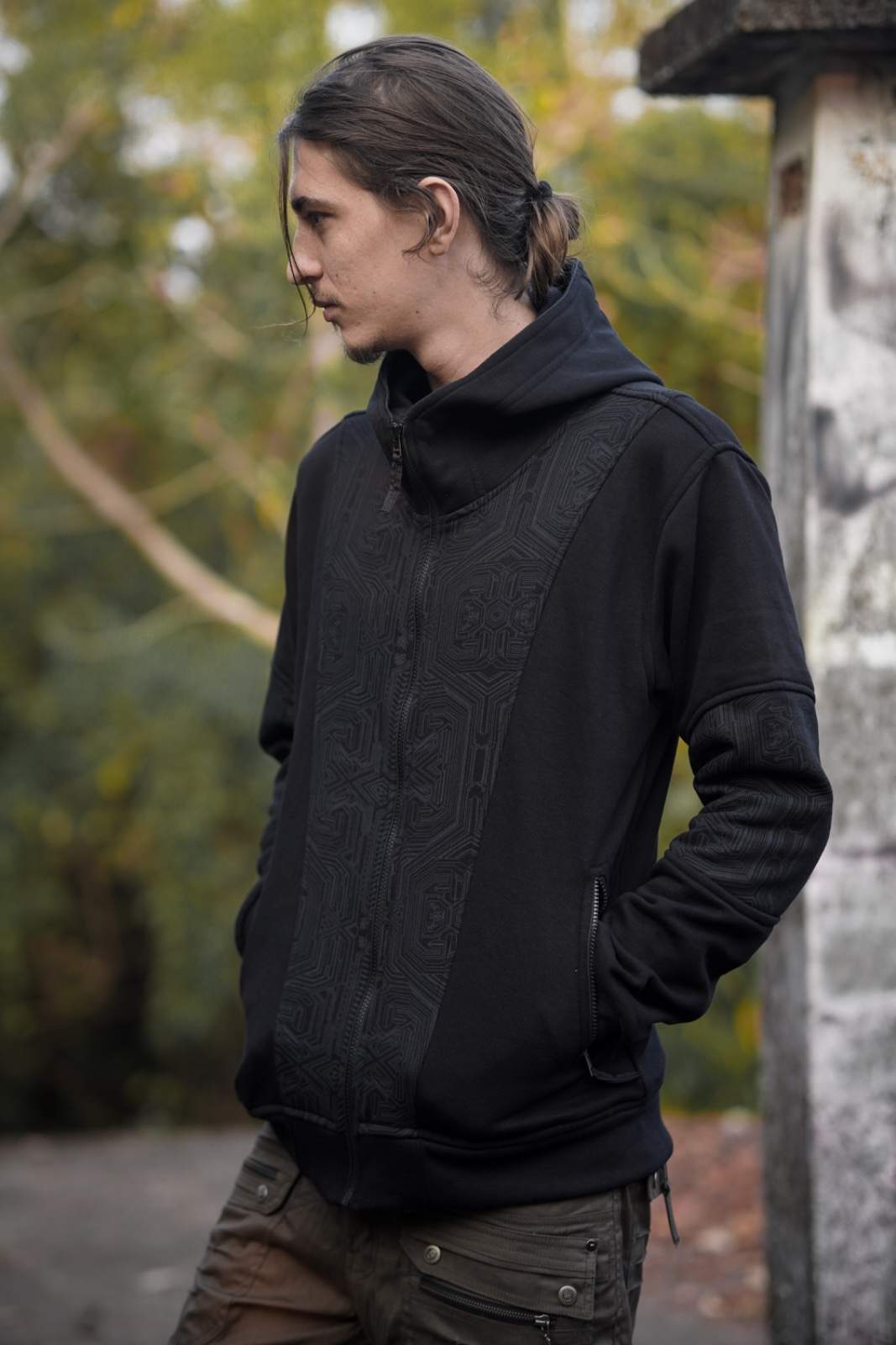 Side view of the Metanoia black hoodie showing geometric chest panels and zippered pockets