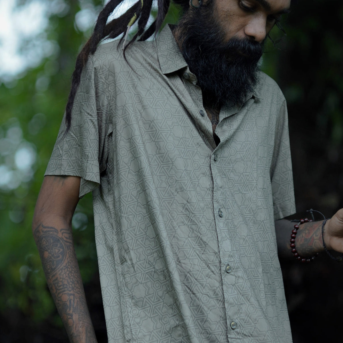 Front view of Pythagoras olive khaki men's viscose shirt with all-over sacred geometry pattern outdoors