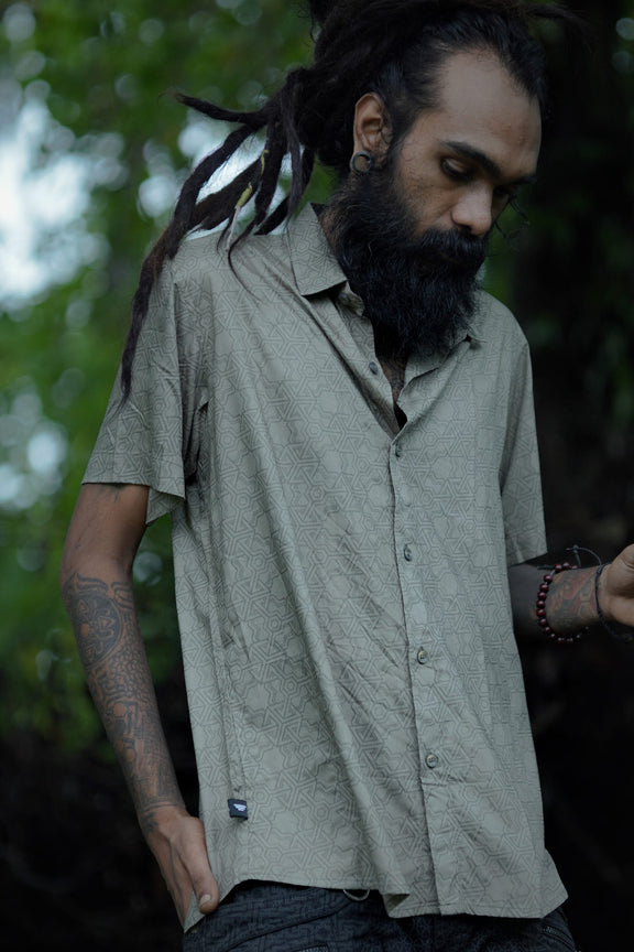 Front view of Pythagoras olive khaki men's viscose shirt with all-over sacred geometry pattern outdoors