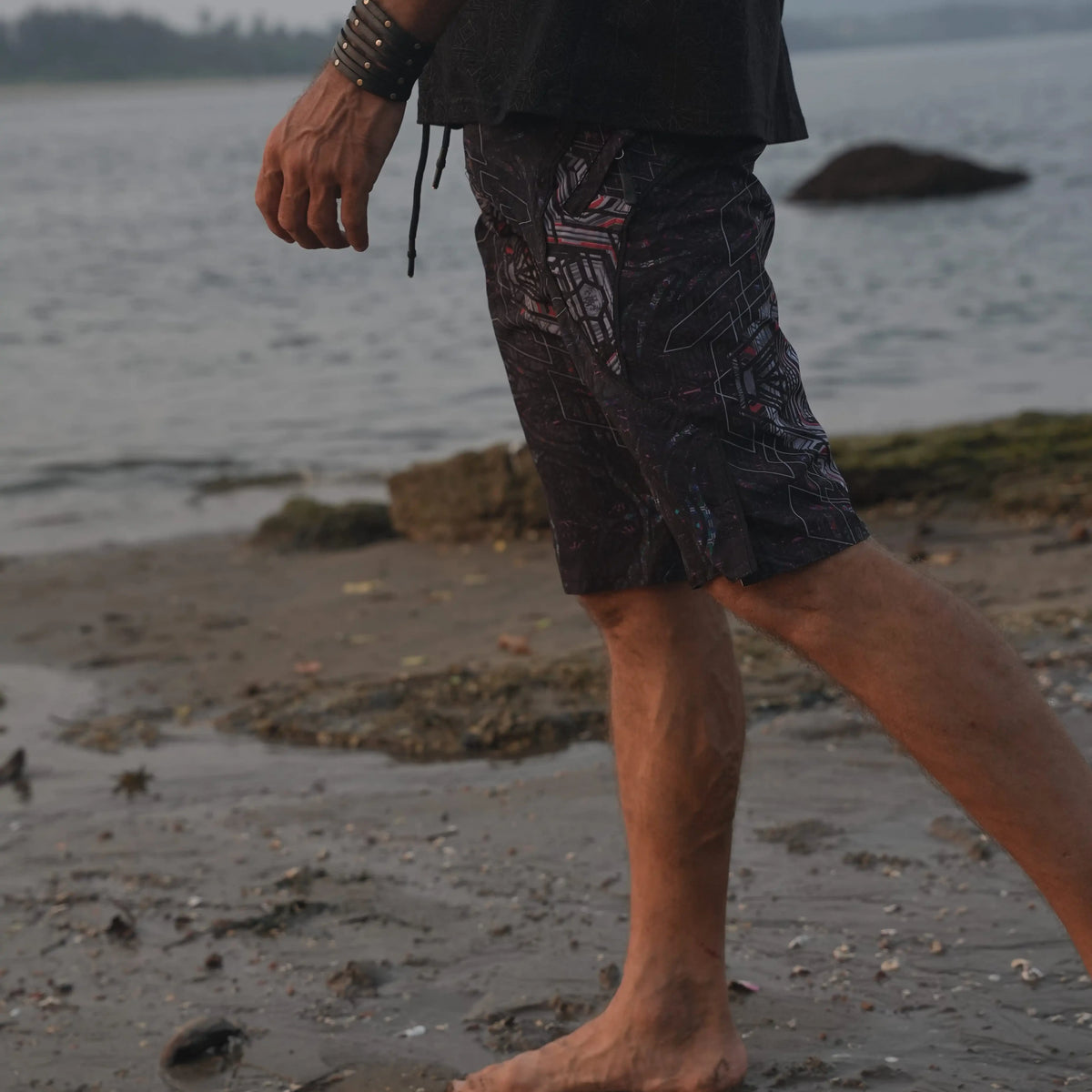 Man wearing Star Dust geometric print board shorts while walking along the beach