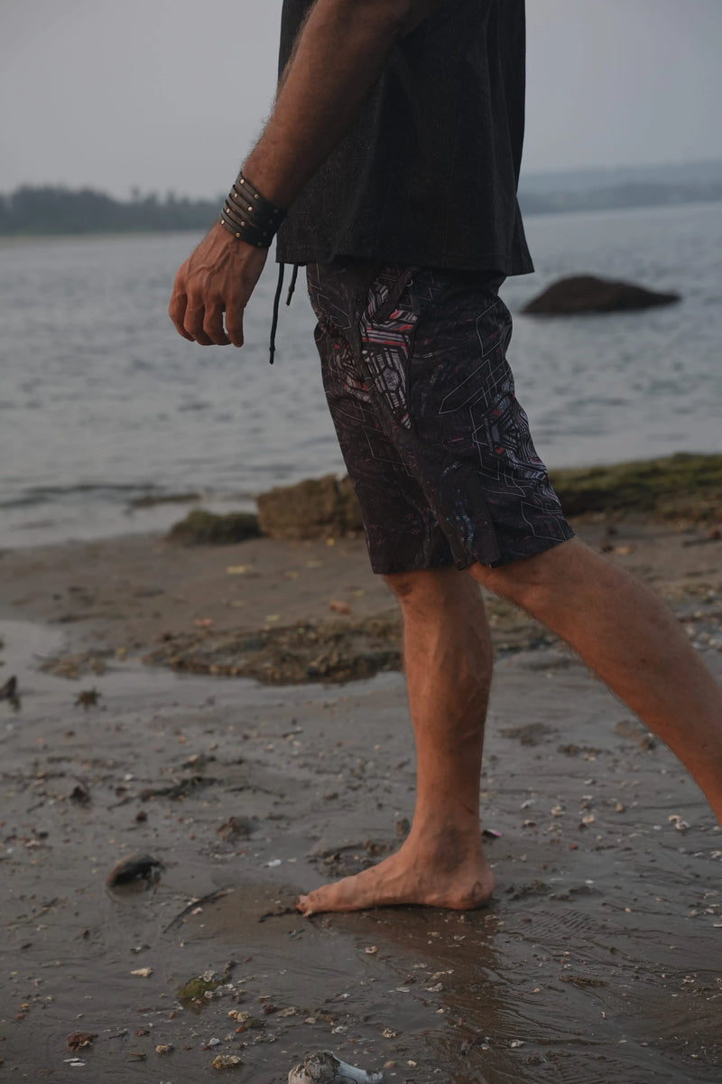 Man wearing Star Dust geometric print board shorts while walking along the beach