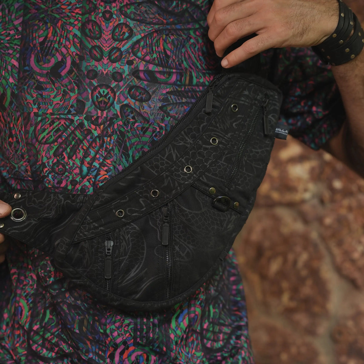 Close-up of the Vanta Dragon bag's strap buckle, metal eyelets and dark patterned fabric